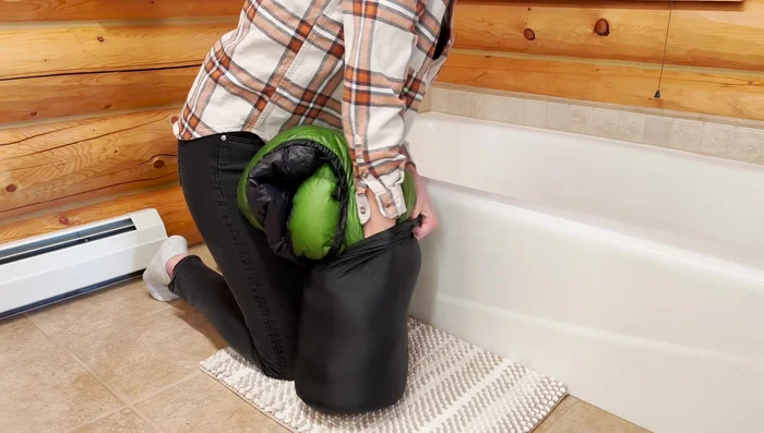 Prepare the sleeping bag: Stuff the sleeping bag into its stuff sack to remove as much air as possible before wetting it.