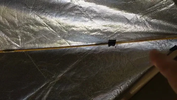 Attach the emergency blanket to the crisscrossed poles using the sewn tabs.