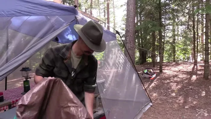Secure the tarp to the center rope using a carabiner through the center grommet of the tarp.