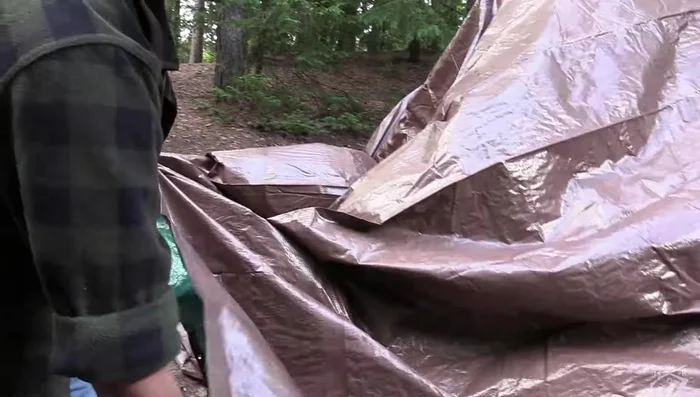 Secure the tarp to the center rope using a carabiner through the center grommet of the tarp.