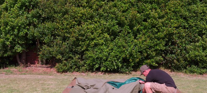 Grab the center top of the tent, pull it to one side, shake it to flatten, and repeat for the other sides.