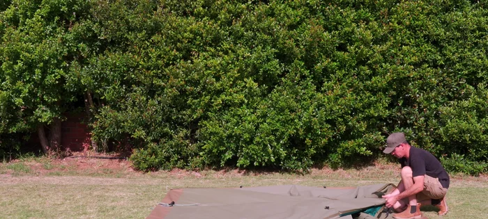 Grab the center top of the tent, pull it to one side, shake it to flatten, and repeat for the other sides.