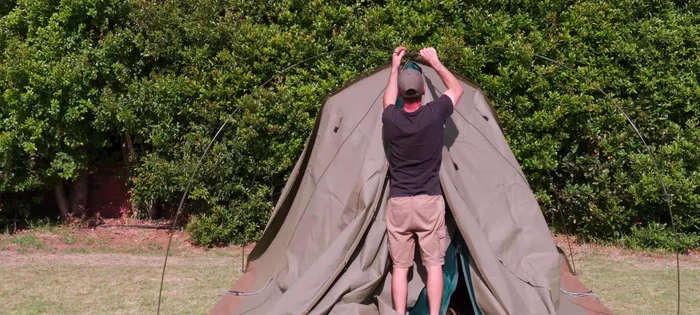 Stand in the doorway, pull down the center of the tent, and remove remaining clips.
