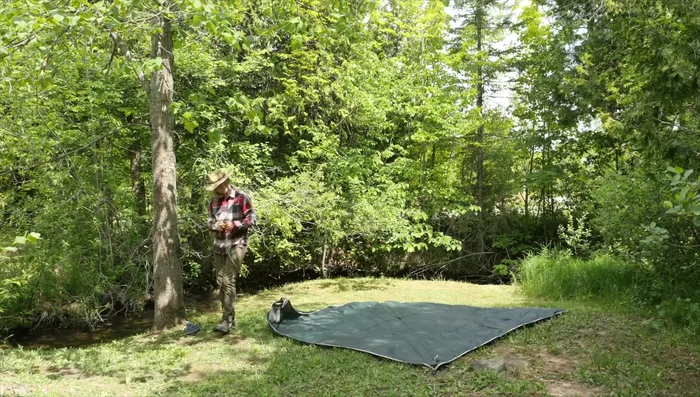 Hoist up the tarp and tie off to the tree trunk.
