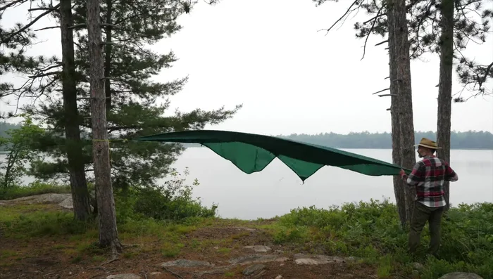Tie opposing corners of the tarp to two trees using Bolin and hitch knots.