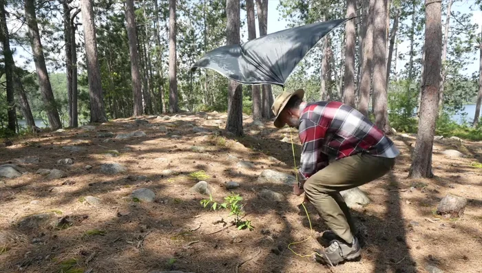 Secure the four corners of the tarp using Bolin and taut-line hitches with stakes.