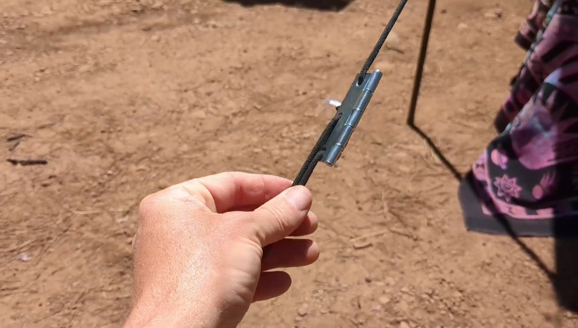 The small metal door hinge being attached to the paracord.