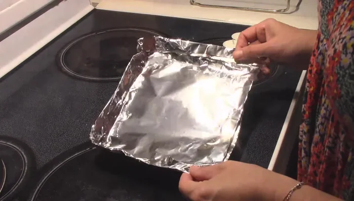 Prepare your tin foil base: Double over a sheet of tin foil to create a double-thick base. Form small walls around the edges to contain the candle heat.