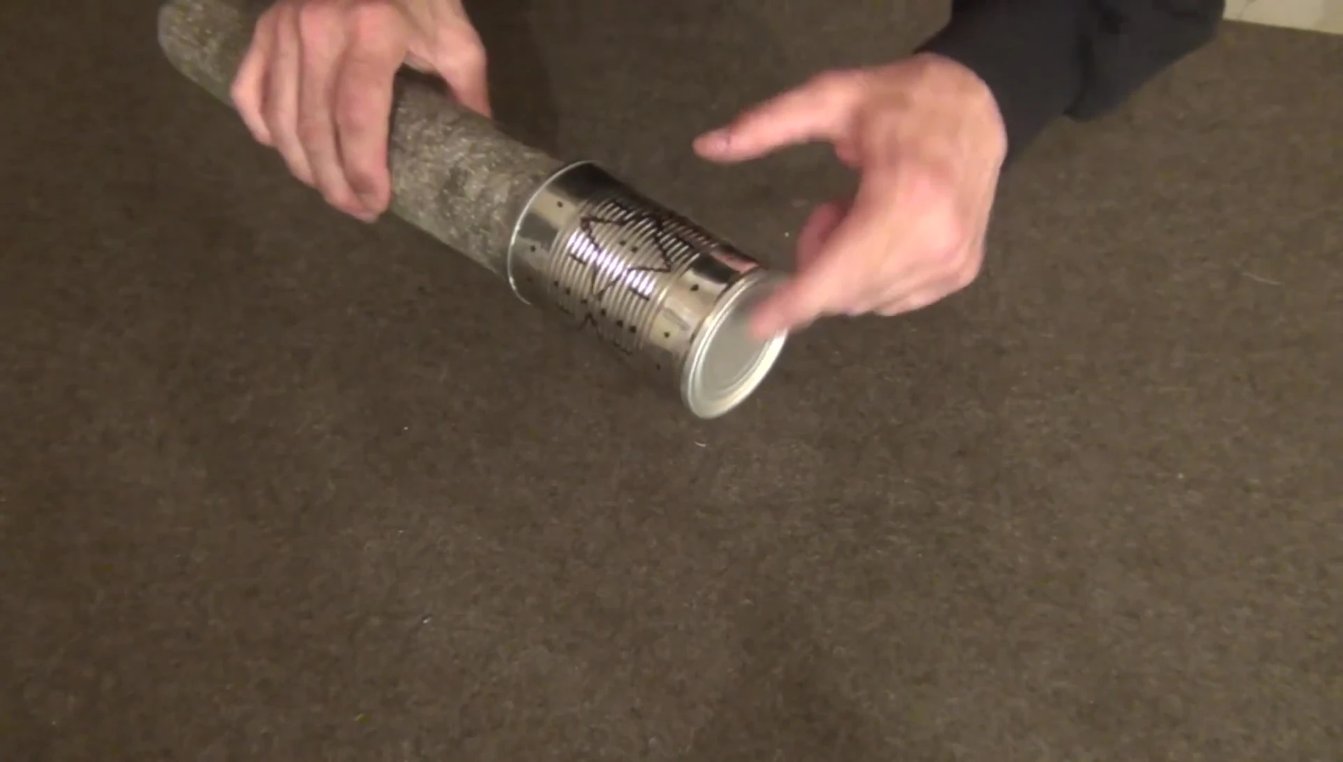 Punching a hole in the tin can with a hammer and nail.