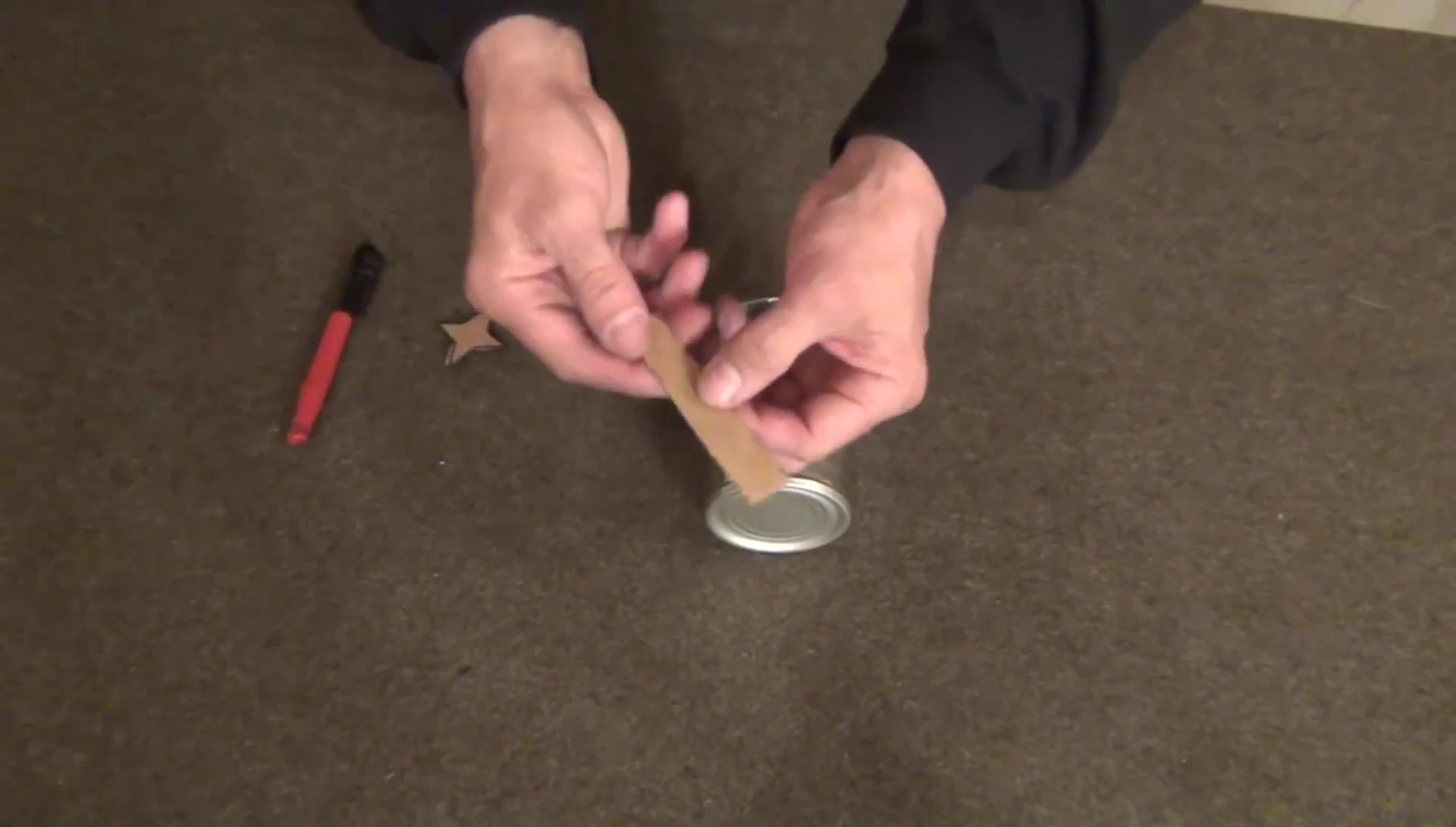 Marking the tin can with a sharpie and cardboard template.