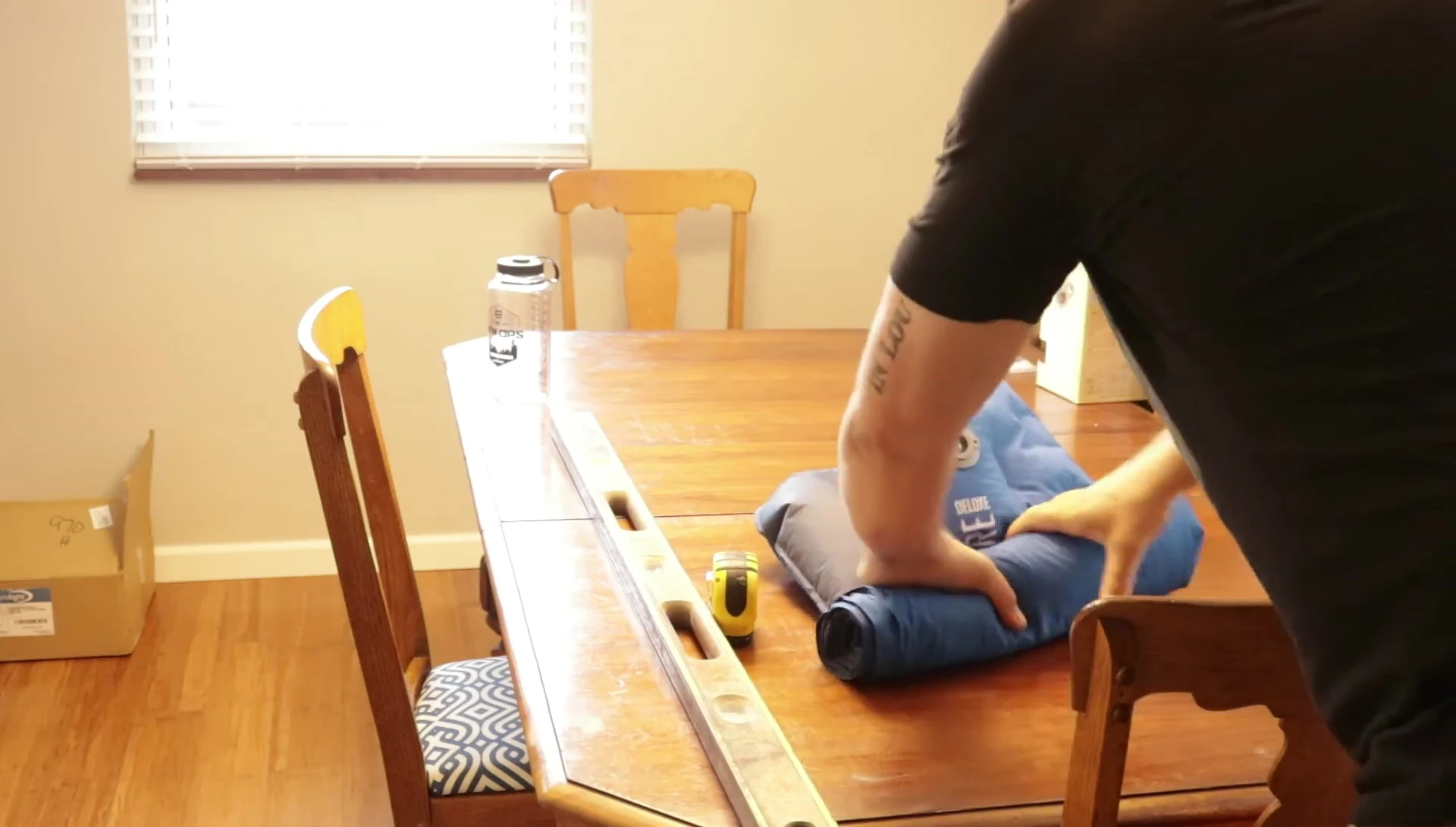 The reviewer deflating and rolling up the sleeping pad.