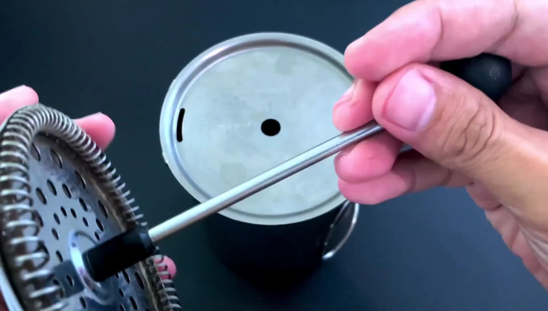 The French press plunger being prepared for insertion.