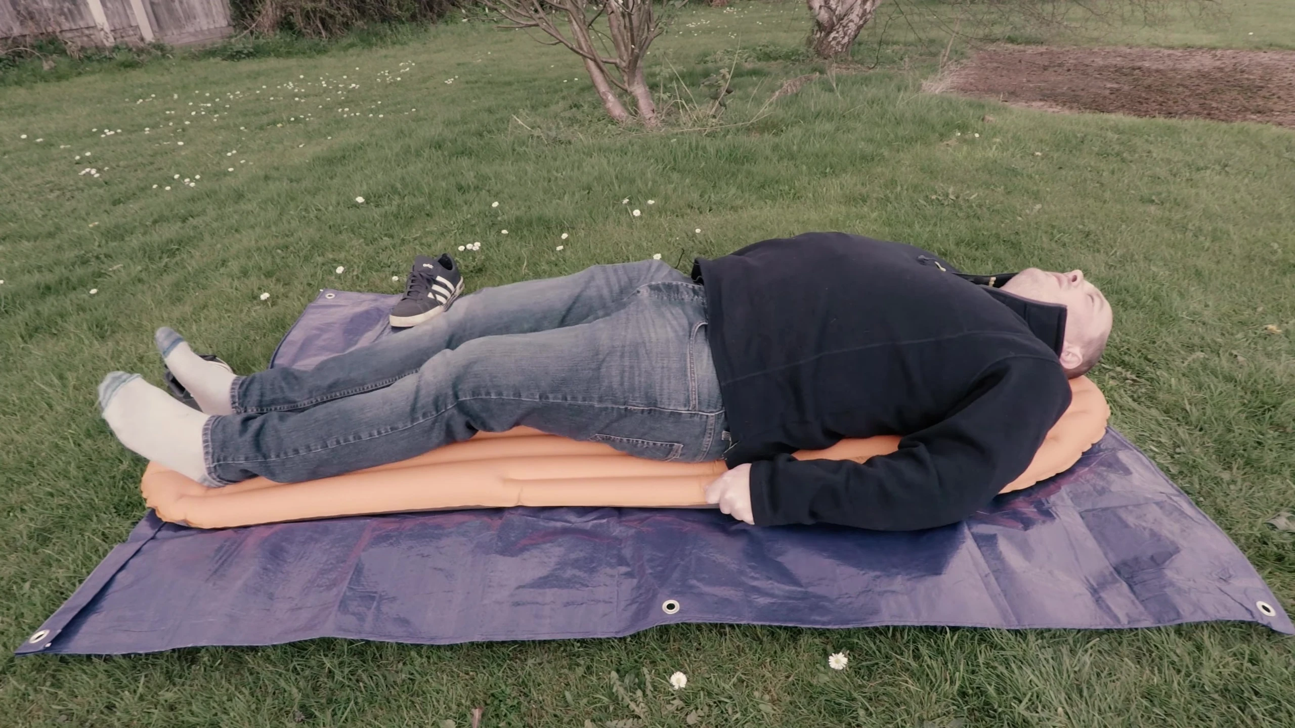 The reviewer lying down on the sleeping pad, demonstrating comfort.