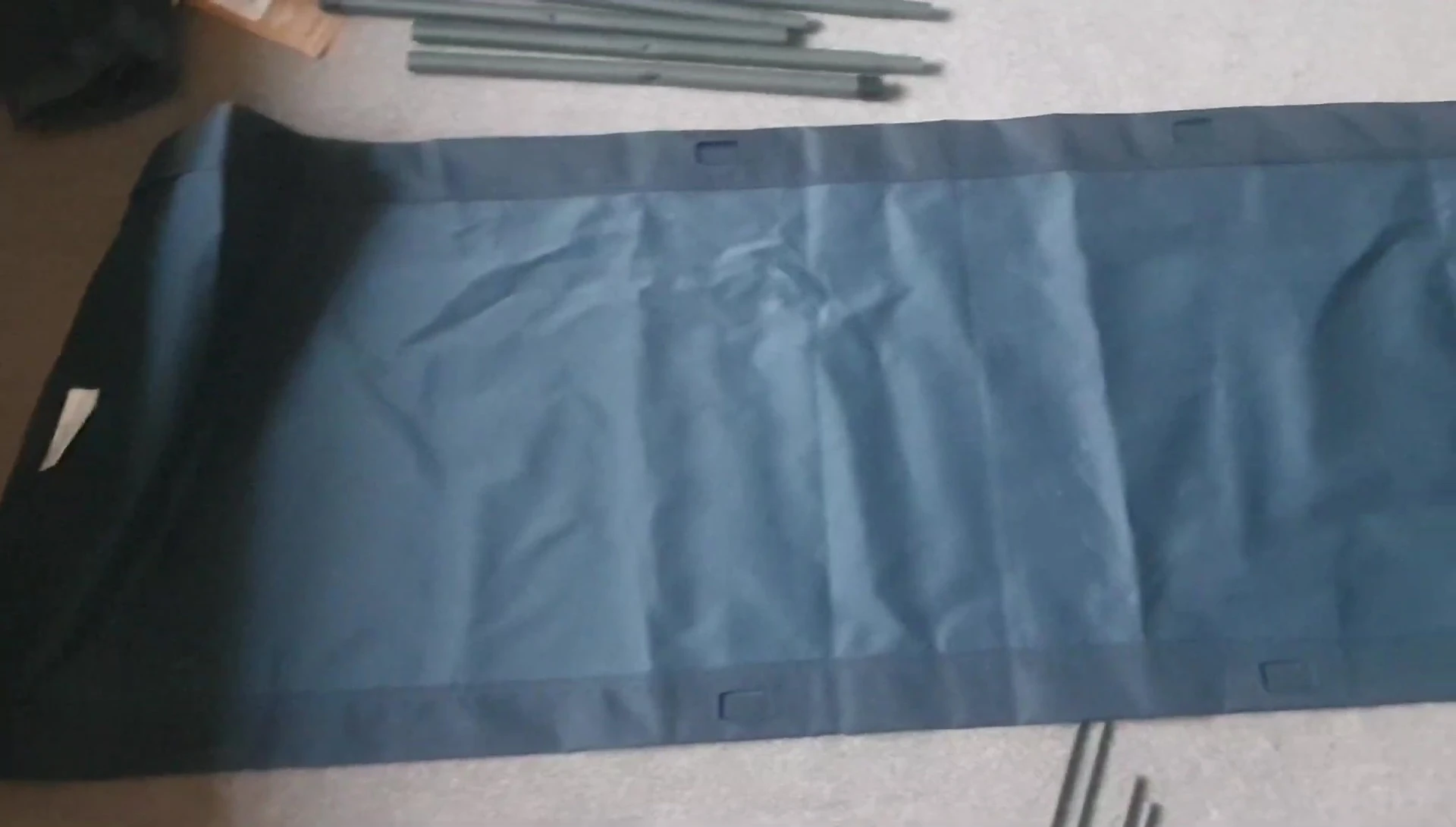 Laying out the camp bed cloth with the holes facing upwards.