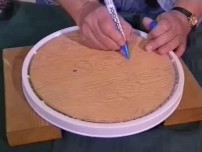 Drill two holes through the plywood and into the plastic lid.