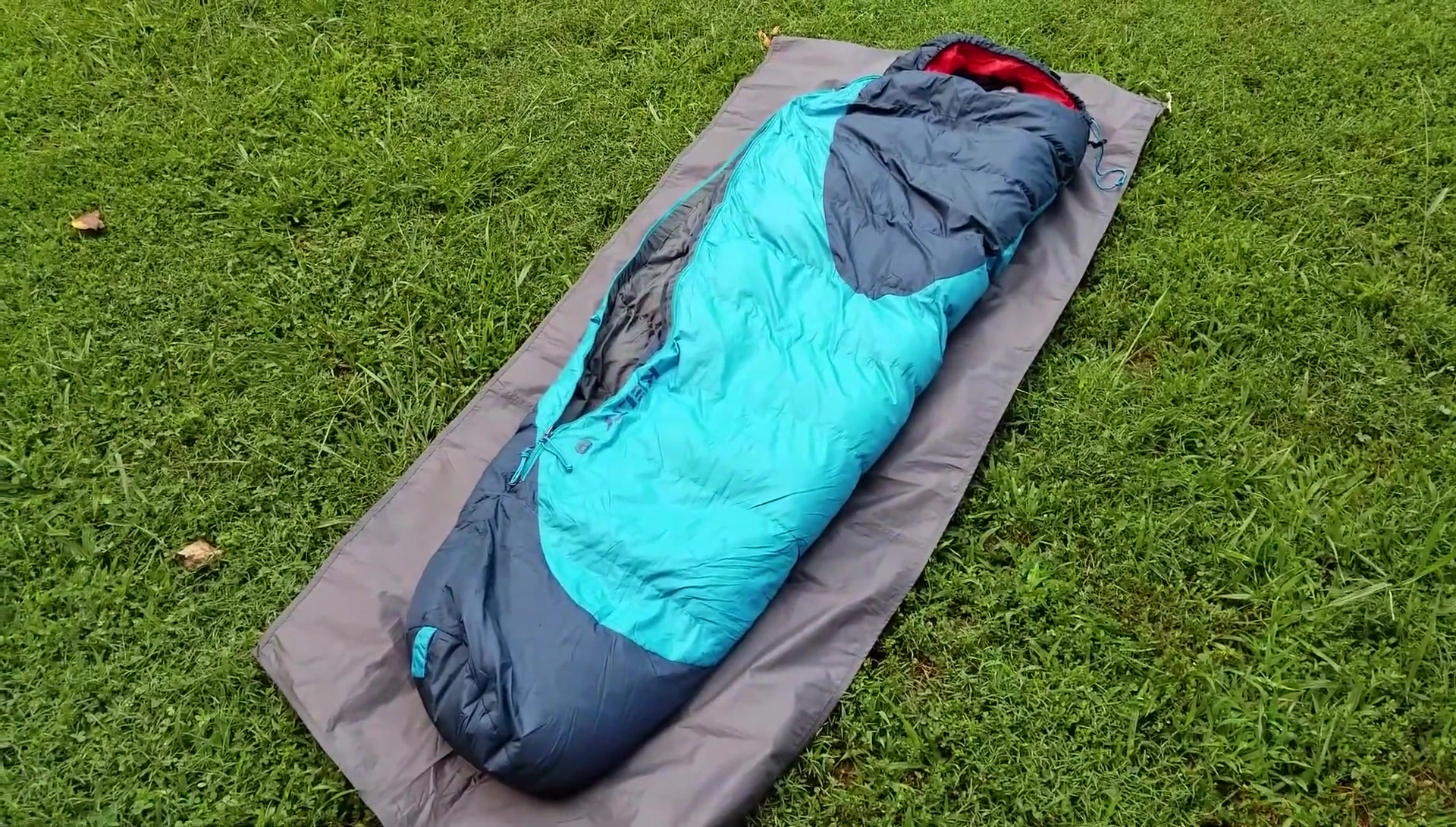 The reviewer holding the sleeping bag, showcasing its size and color.