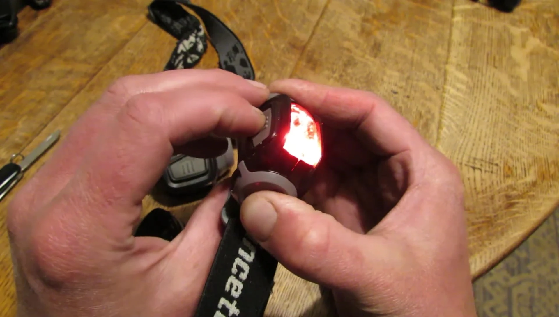 The presenter demonstrates closing the loose battery door on the Princeton Tec Remix.