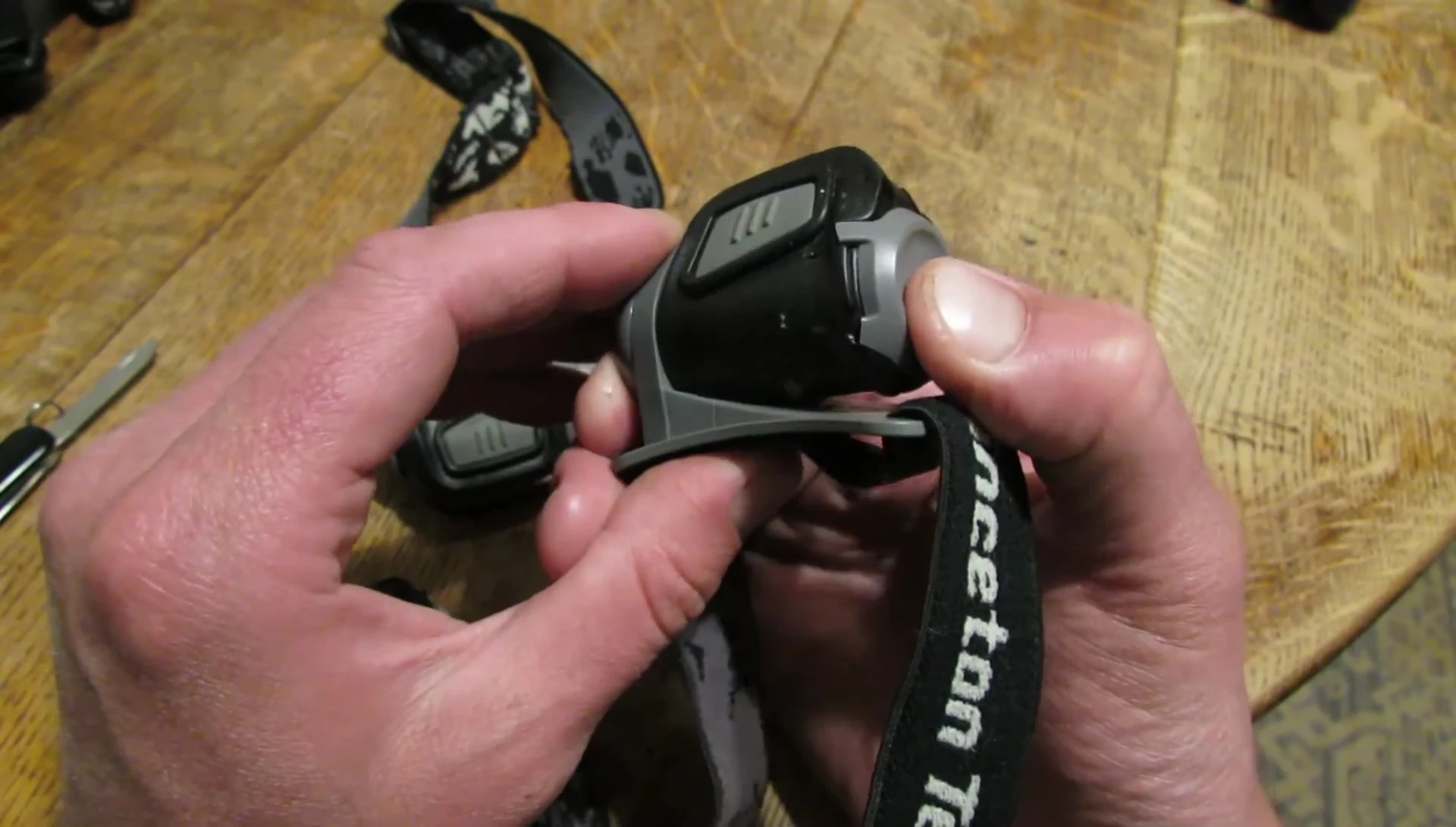 The presenter shows a headlamp with duct tape securing the broken battery door.