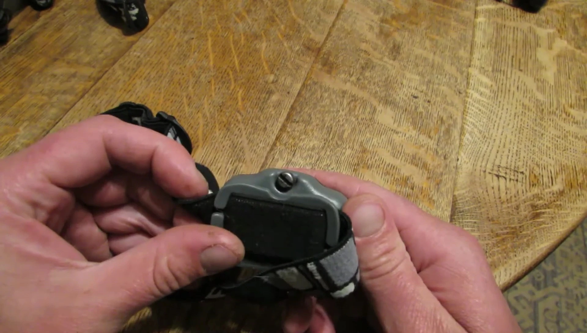 The presenter shows a Princeton Tec Vizz headlamp and demonstrates its screw-on battery compartment.