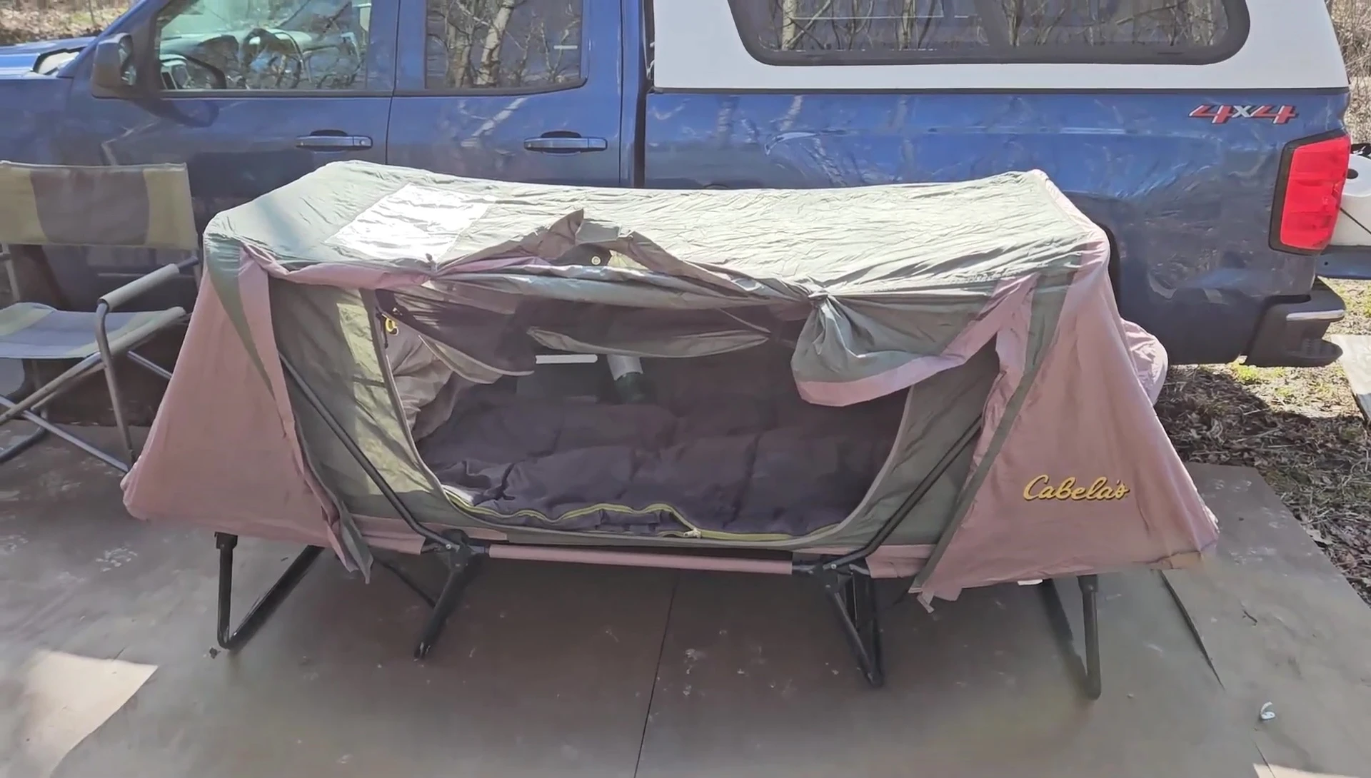 The cot tent set up next to a vehicle.