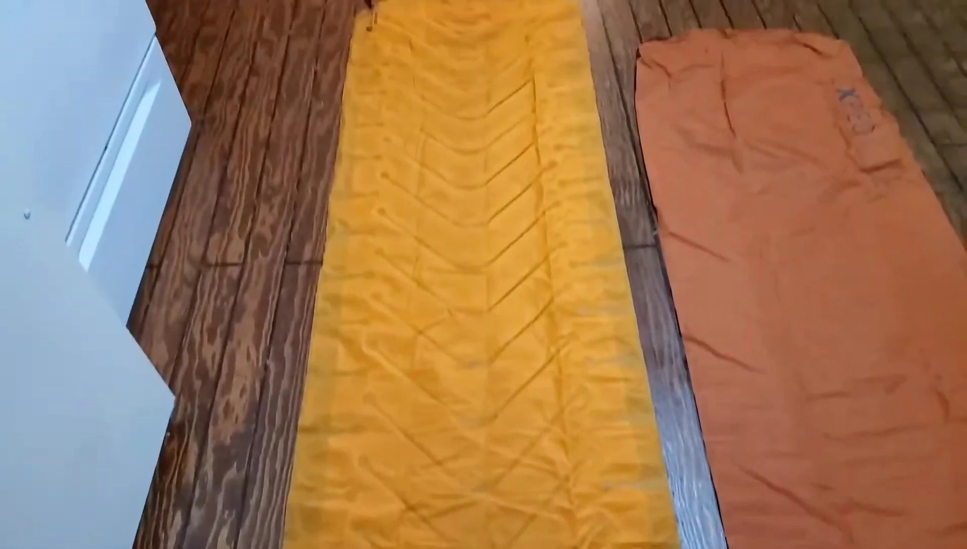 Deflated Exped Synmat 9 and Klymit Insulated Static V Lite sleeping pads side-by-side, showcasing the size difference.