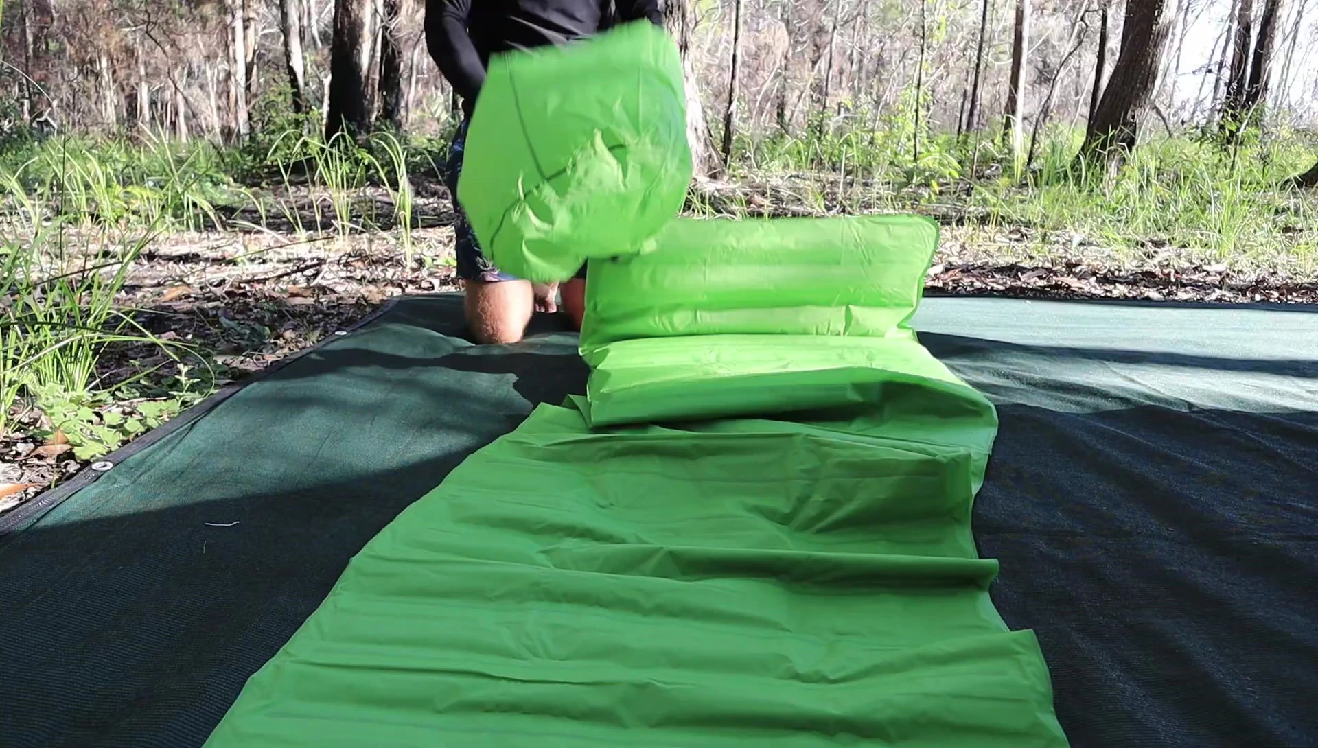 Person using an inflation bag to inflate the thicker sleeping pad.