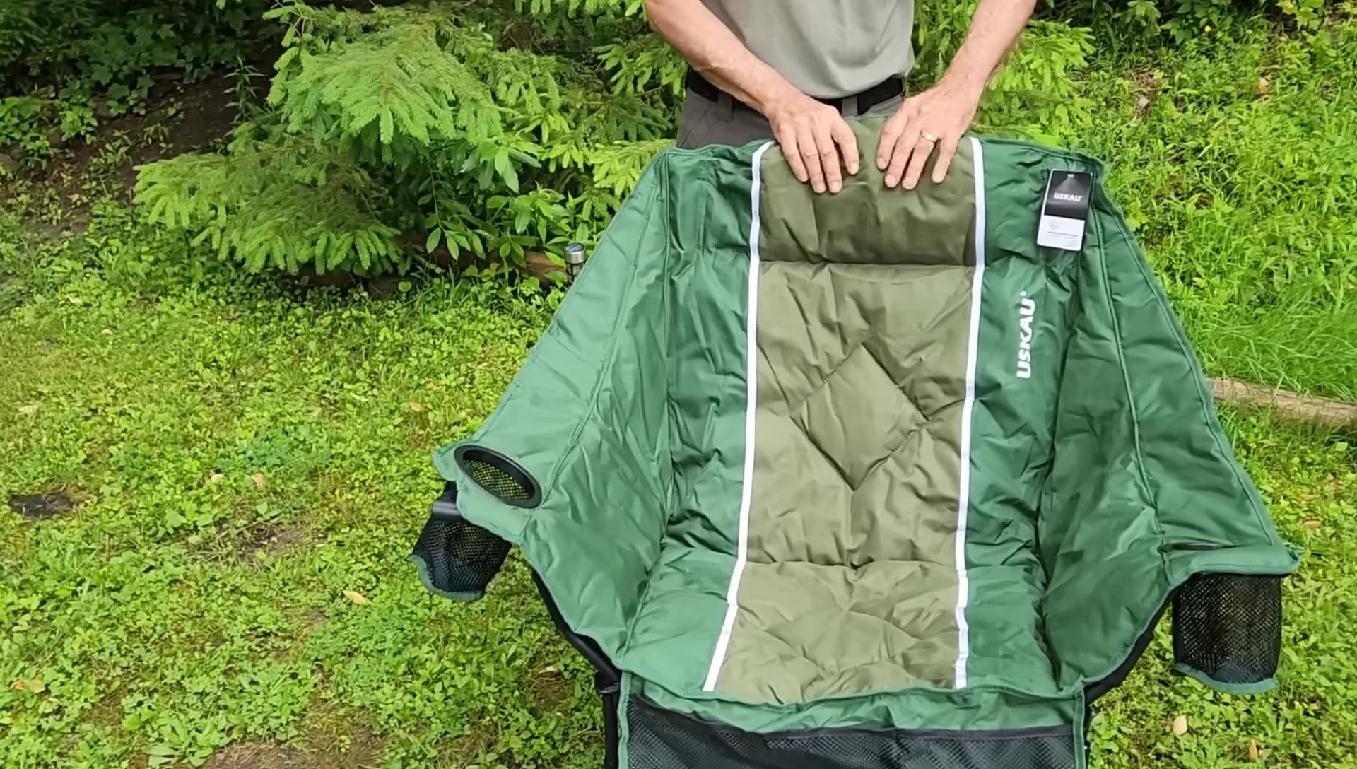 The chair unfolded, showcasing its olive and forest green color scheme and plush pillow.