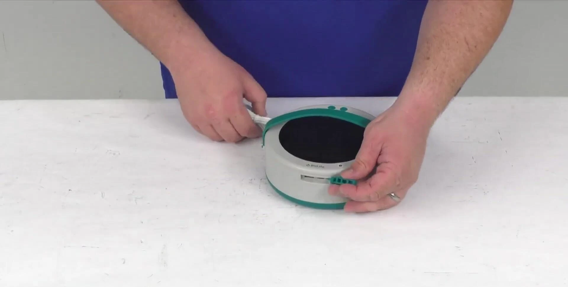 The presenter shows the USB charging port and the carrying handle.