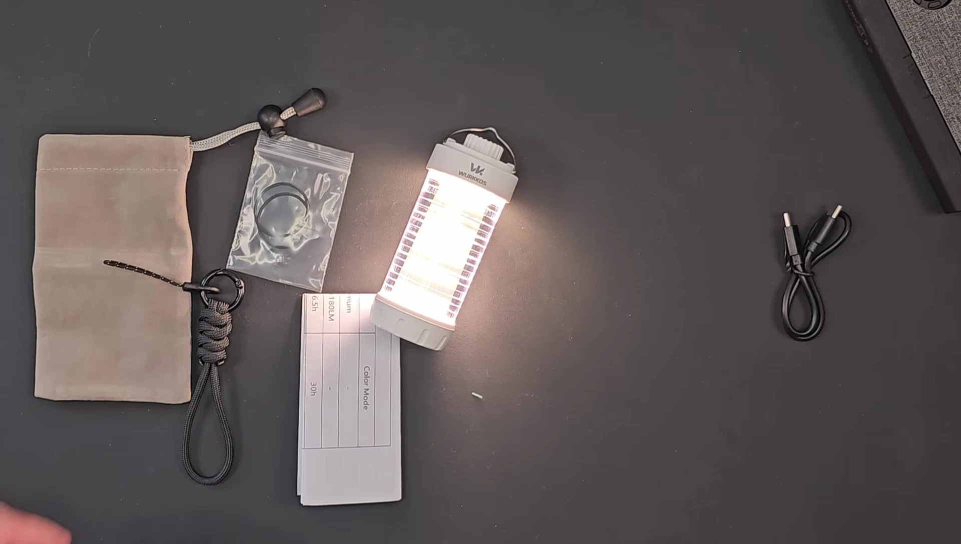 Close-up of the lantern's packaging contents: USB-C charging cable, O-rings, and pouch.